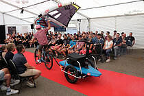 Ein Mann fährt mit dem Velo über einen roten Teppich.