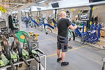 Ein Mann in kurzen Hosen und T-Shirt arbeitet an einem Fahrrad.