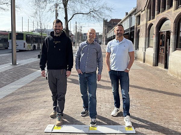 Drei Männer stehen auf einem Gehweg.