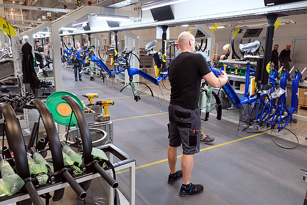 Ein Mann arbeitet in einer Fahrradfabrik an einem Montageband. 