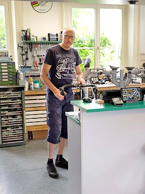 Ein Mann steht in einer Fahrradwerkstatt.