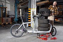 Cargobikes im professionellen Einsatz. Ein Mann lädet Autoersatzreifen auf ein Lastenrad.