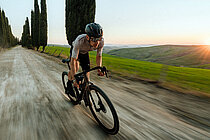 Ein Gravelbiker fährt auf einem Schotter-Weg.